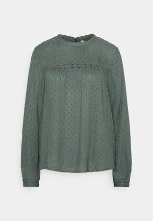 Groene blouse met lange mouwen van textuurstof, met een kantdetail op de borst en een losse, relaxte pasvorm. Subtiel reliëfpatroon door het geheel.