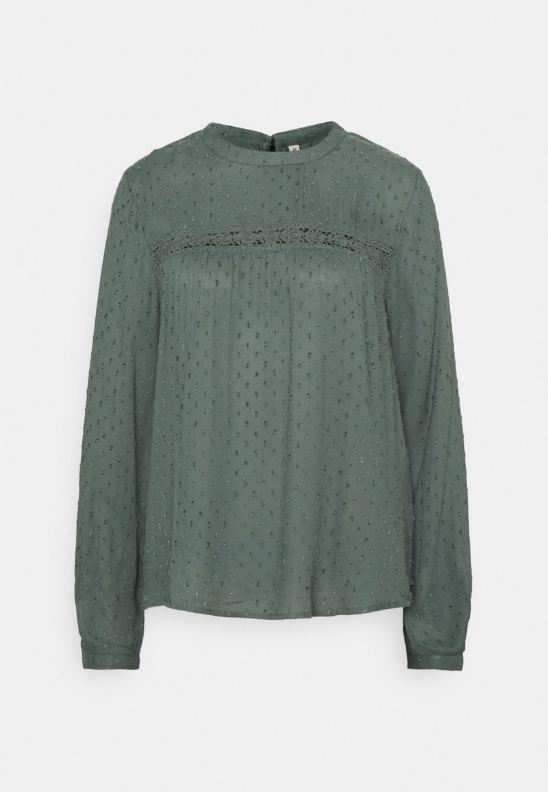 Blouse verte à manches longues en tissu texturé, avec un détail en dentelle sur la poitrine et une coupe ample et décontractée. Motif en relief subtil sur l'ensemble.