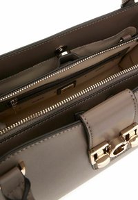 Sac à main en cuir synthétique gris avec des détails en or, comportant des compartiments zippés et une texture lisse. L'intérieur comprend plusieurs poches.