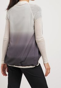 Vícevrstvý svetr s gradientem od světle šedé po tmavě šedou. Pletené horní rukávy, hladké dolní tělo, žebrovaný lem a neutrální barvy.