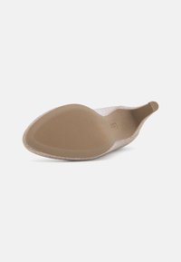 Chaussure beige à talon haut et bout pointu, montrant une semelle en caoutchouc texturée antidérapante et un talon élancé sur fond blanc.