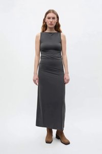 Graues ärmelloses Maxikleid mit tailliertem Oberteil und Drapierungsdetails, kombiniert mit braunen Stiefeletten. Glatter, elastischer Stoff.