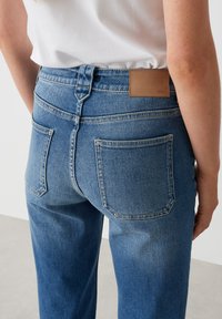 Blauwe denim jeans met een hoge taille, met een soepele textuur, twee achterzakken en een bruine leren label op de taille.
