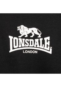 Crna pamučna majica s bijelim grafičkim prikazom lava i natpisom "LONSDALE LONDON" u luku ispod, s teksturiranim, rebrastim materijalom.