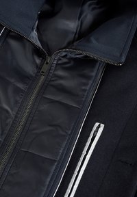 Chaqueta navy con cremallera, que presenta un forro interior suave, un exterior texturizado y detalles en cremallera blanca contrastantes.