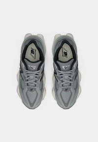 Ein Paar graue New Balance 9060 Laufschuhe, von oben betrachtet, mit Schwarz- und Weißdetails sowie weißen gepolsterten Sohlen.