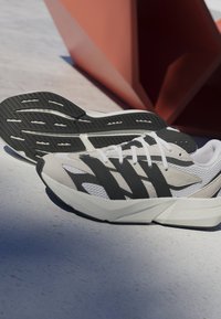 Lightweight running shoes in gray, black stripes, and white accents. Features mesh fabric, rubber soles, and a visible brand name "LIGHTSTRIKE."