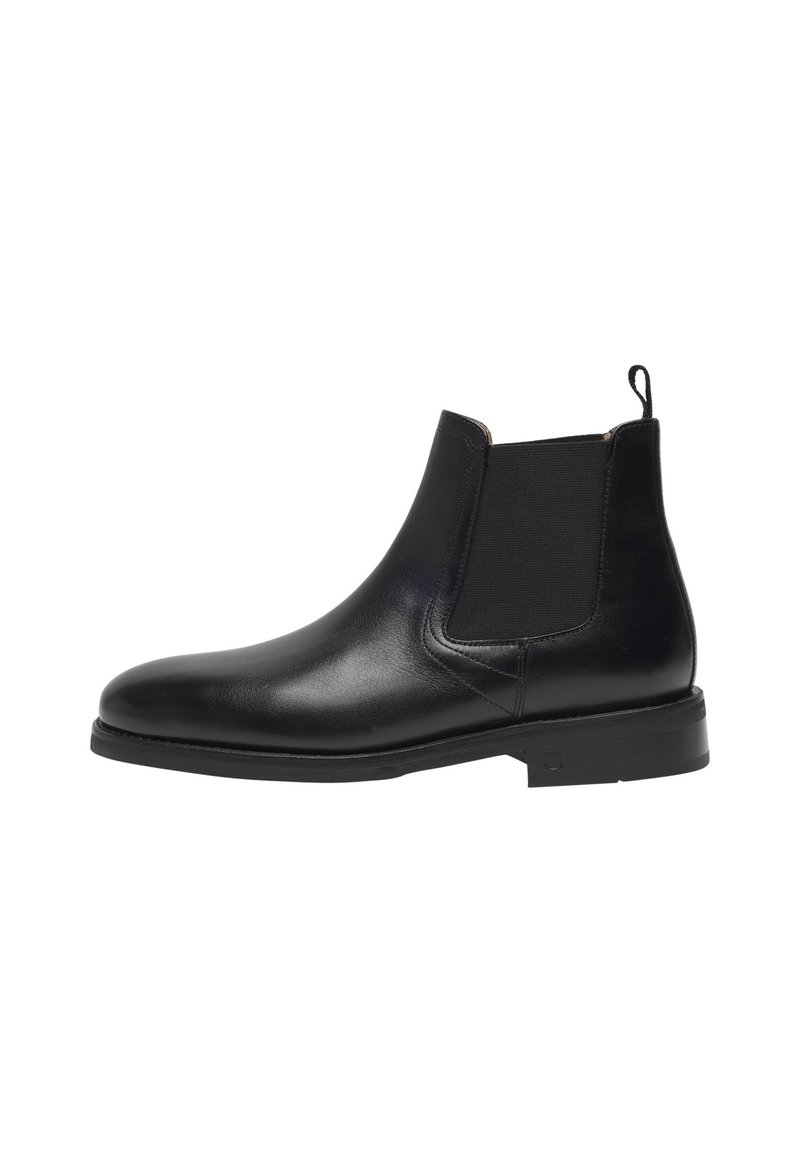 Bottine Chelsea en cuir noir avec des panneaux élastiques sur les côtés, bout rond et une languette à l'arrière. Semelle robuste avec un talon bas.