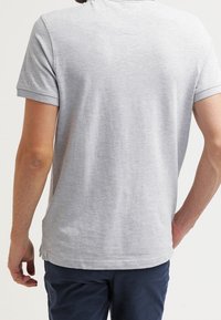 T-shirt gris à manches courtes en coton, avec un col rond et un ourlet droit avec des fentes latérales, vu de dos.