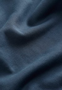 Tissu en coton bleu marine avec une texture lisse, présentant des plis subtils et un motif de tissage régulier.