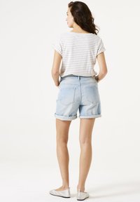 Top de manga corta con rayas suaves, combinado con pantalones cortos de denim azul claro, con un ajuste relajado y bolsillos. Calzado: bailarinas plateadas.