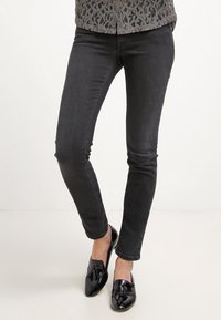 Svarta skinny jeans i bomullsblandning, med en slät yta och subtil elastiskhet. Kombinerade med glänsande svarta loafers.