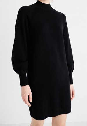 Zwarte gebreide jurk met een hoge geribde kraag, puffmouwen en geribde manchetten. Glad materiaal en knielange pasvorm. Eenvoudige en gestroomlijnde vorm.