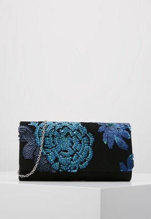 Bolso de mano negro con patrones florales de lentejuelas azules y una correa de cadena plateada, descansando sobre una superficie blanca.