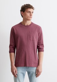 Burgunderfarbenes Langarm-T-Shirt mit rundem Ausschnitt und Brusttasche; aus weichem Stoff mit leicht strukturierter Oberfläche.