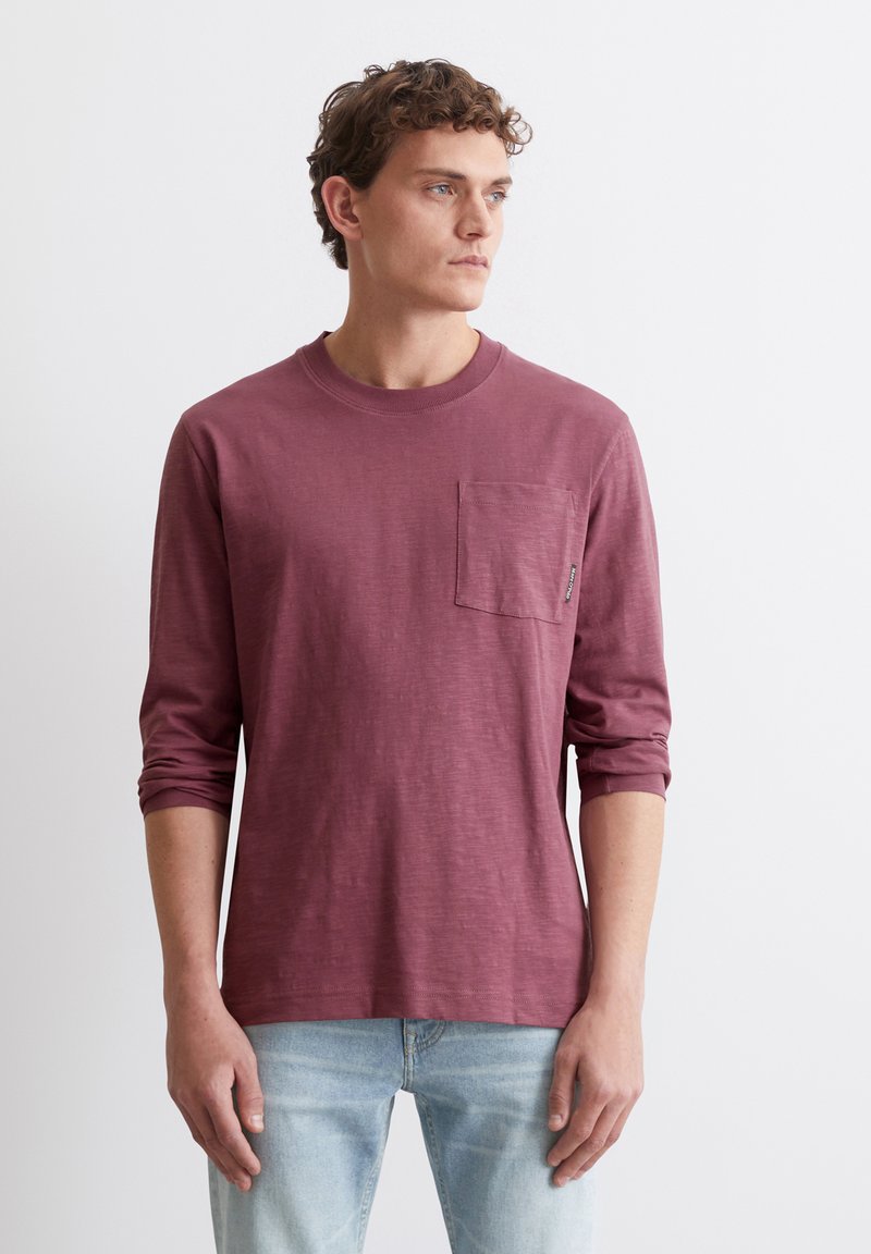 Burgunderfarbenes Langarm-T-Shirt mit rundem Ausschnitt und Brusttasche; aus weichem Stoff mit leicht strukturierter Oberfläche.