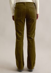 Olijfgroene corduroy flared broeken met een gestructureerde afwerking, voorzien van twee achterzakken en een middenhoogte tailleband.