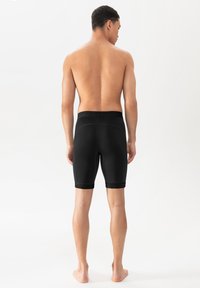 Schwarze Sportshorts mit einer enganliegenden Passform und glatter Textur, mit einem Bund und knielangem Schnitt, von hinten betrachtet.