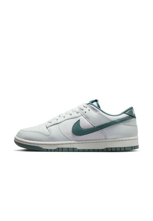 Hvid lavtop Nike sneaker med grønt Swoosh-logo, grøn kant og en tyk hvid sål med grønne ydersålsaccents.