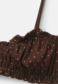 Brown polka dot bikini top, featuring orange dots, ruffled edges, and adjustable straps made of textured fabric.