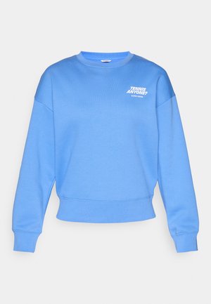 Sweat-shirt bleu clair avec un col rond, des épaules tombantes et des poignets côtelés. Inscription en blanc : "TENNIS QUELQU'UN ? BJÖRN BORG."