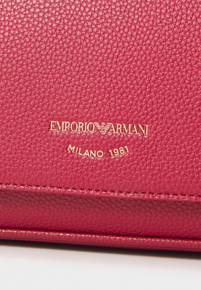 Portofel din piele roz cu o suprafață texturată, logo-ul „Emporio Armani” embosat și „Milano 1981” scris cu litere aurii.