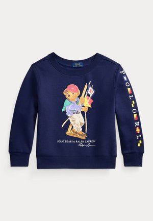 Ναυτικό μπλε φούτερ με τον αρκούδο Polo ντυμένο με ναυτικό σύνολο που κρατά ναυτικά σημαίες, κείμενο "POLO RALPH LAUREN" στο μανίκι και λογότυπο κάτω από τον αρκούδο.