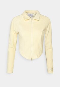 Geel corduroy cropped jasje met een kraag, voorzien van een voorrits, lange mouwen en subtiele ribbelstructuur. Accentlabel op de mouw.