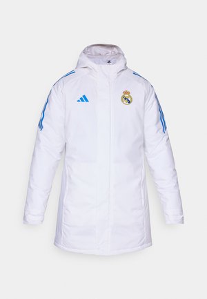 Veste isolée blanche avec une capuche, dotée de rayures bleues et du logo du Real Madrid sur la poitrine. Fabriquée en matériau lisse et résistant aux intempéries.