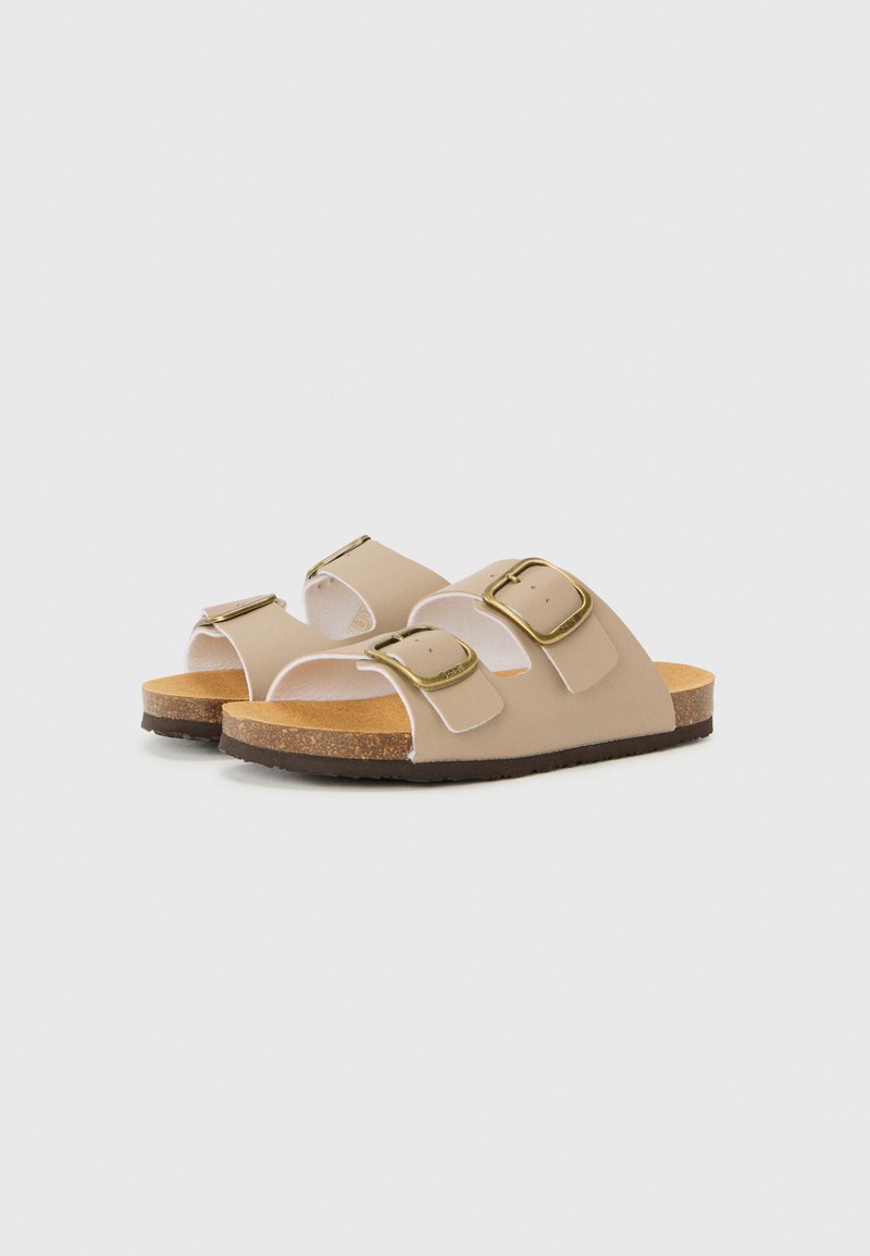 Sandales beiges avec deux sangles ajustables, boucles en ton doré, semelle en liège et semelle en caoutchouc. Texture lisse, design ouvert et décontracté.