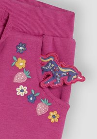 Fuchsia katoenen shorts met geborduurde bloemen en aardbeien, met een eenhoornpatch op de zak. Geribbeld tailleband.