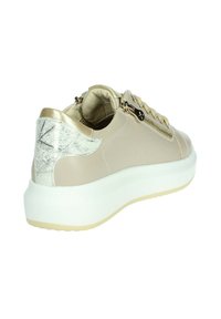 Sneaker beige chiaro con un accento argento texturizzato sul tallone, dettagli in metallo dorato e una suola piatta bianca. Presenta una cerniera laterale.