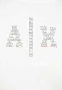 Λευκό βαμβακερό μπλουζάκι με μεγάλα, διακοσμημένα με ασημένιες πέτρες στρας γράμματα «A/X» πάνω από το κείμενο «ARMANI EXCHANGE» με διακριτικό τύπωμα.