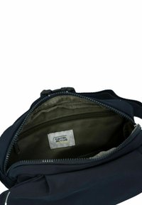 Granatowa torba materiałowa z zamkiem błyskawicznym, z zielonym wnętrzem i metką oznaczoną "camel active". Zawiera wewnętrzną kieszeń.