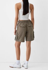 Olivgrön cargoshorts med elastisk midja, två framfickor och två sidofickor. Tillverkade av bomullstyg med en slät textur.