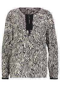 Blusa a maniche lunghe bianco e nero con motivo a zebra ondulato, scollo rotondo e una patta centrale con dettaglio a fiocco. Tessuto morbido.
