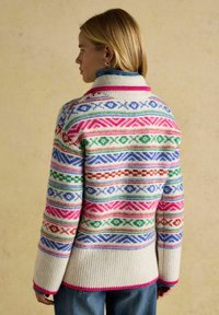 Bunter gestrickter Cardigan mit geometrischen Mustern in Pink, Grün, Blau und Rot auf einem cremigen Grund. Verfügt über einen gerippten Saum und einen hohen Kragen.
