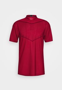 Röd kortärmad polo skjorta tillverkad av andningsbart tyg med ett strukturerat mönster. Har en mandarinkrage och geometriska designelement.