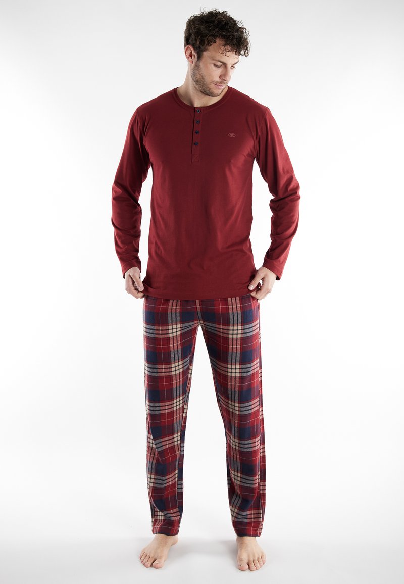 Rode longsleeve shirt met een geknoopte kraag, gecombineerd met geruite broek met rode, marineblauwe en crèmekleurige strepen. Zachte stof, relaxed fit.