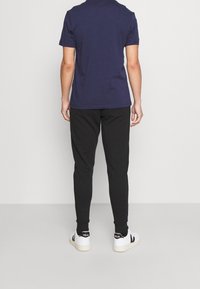 Námořnické tričko s krátkým rukávem spojené s černými tepláky a bílými teniskami. Tento outfit má volný střih a jednoduchý design.