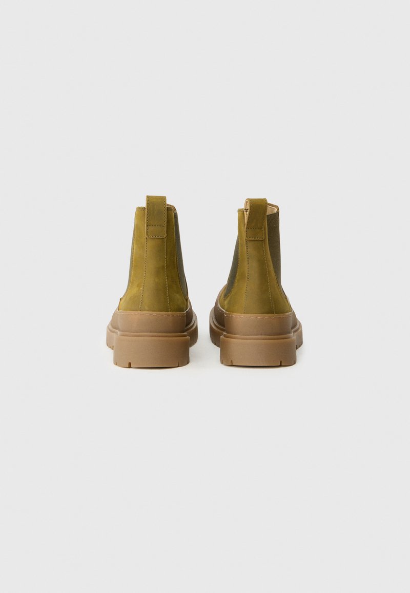 Bottines en cuir vert olive avec des semelles en caoutchouc marron, des panneaux latéraux élastiques et des languettes à l'arrière pour un enfilage facile.