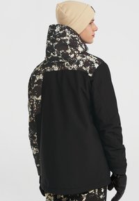 Zwarte en gepatternde jas met een capuchon, textuurstof met een spetterontwerp in wit en bruin op de bovenrug, en aansluitende manchetten.