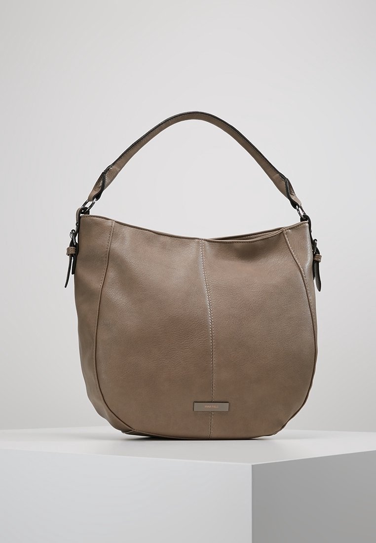 Sac à main hobo en cuir taupe avec une seule sangle d'épaule, une forme incurvée, des coutures apparentes et une petite plaque métallique rectangulaire de la marque sur le devant.