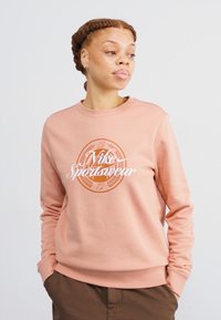 Rosa hettegenser med rund hals og lange ermer. Har en sentral logo i hvit og oransje med laurbærdekor, laget av mykt stoff.