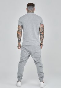 Gray cotton t-shirt and matching sweatpants set, featuring a relaxed fit and ribbed cuffs, worn with white sneakers.