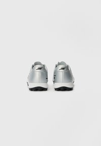 Silver athletic shoes with a smooth upper, black accents, and a textured rubber sole. Features a logo on the heel and streamlined design.
