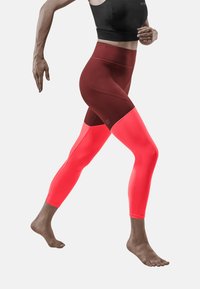 Leggings au design ajusté en bordeaux et rose fluo, avec une partie inférieure texturée, une taille haute et des panneaux de couleurs contrastantes.