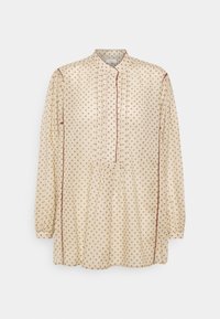 Blusa a maniche lunghe color crema con pois marroni, scollatura a bottoni e dettagli plissettati. Tessuto morbido con bordi a zigzag.