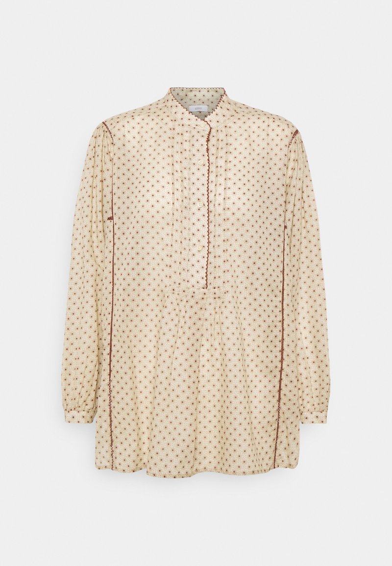 Blusa a maniche lunghe color crema con pois marroni, scollatura a bottoni e dettagli plissettati. Tessuto morbido con bordi a zigzag.