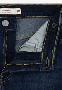 Jeans super ajustados de talle alto en denim oscuro. Presentan una cremallera, costuras doradas y una etiqueta con la talla 10. Bolsillo interior en tela gris claro.